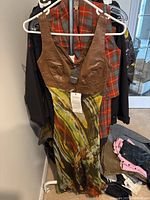 Full view of the dress hanging showing the brown leather bodice and multicolor printed skirt.