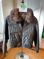 Front view of black quilted jacket with fur collar and ribbed cuffs and waistband.