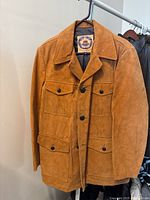 Front view of the brown suede vintage men's oversize jacket with button closure and four flap pockets.