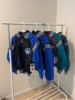 Four satin bomber jackets on clothing rack showing two Maple Leafs and two Ducks jackets