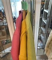 Three pastel-colored vintage suit sets hanging on a clothes rack.