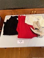 Overview photo showing black suede skirt, red garment, cream knit sweater, and beige leather boots arranged on table