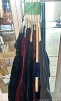 Side view of velvet garments on hangers showing the variety of colors: black, burgundy, rust, blue.
