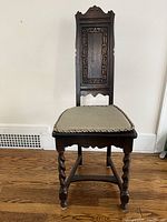 Front view of dark wood carved side chair with upholstered seat and twisted front legs
