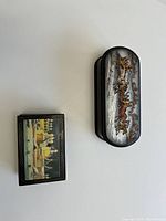 Two decorative enameled curved and rectangular curio boxes with painted top scenes and hinged lids