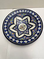Top view of the painted pottery bowl showing intricate blue, white, yellow and black geometric and floral designs.