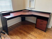 Photo of full corner desk from left side showing surface, sliding trays, open shelves, drawers