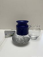 Photo showing the metallic flower stand with silver wire design, clear scalloped glass vase, and a dark blue ceramic vase.