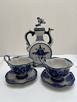 Coffee set items including pot, two cups, and two saucers in blue and white ceramic with floral patterns.