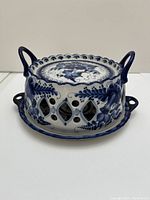 Front view of the ceramic serving dish with openwork handled cover showing the blue floral patterns and diamond-shaped cutouts on the cover.