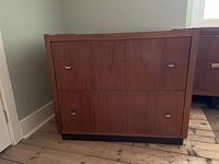 Front view of rectangular wood 2-drawer filing cabinet with metal drawer handles.