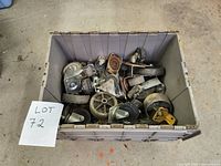 Plastic bin filled with assorted caster wheels of various sizes and materials, some showing wear and rust
