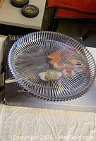 Large clear glass platter with ribbed texture and scalloped edge, placed on a box.