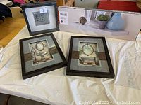 Photo shows boxed white floating shelf with product image and three picture frames, two with vintage clock art and one smaller black frame with monochrome design.