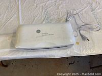 Closed white plastic case labeled 'GE Carving Set' with attached power cord.