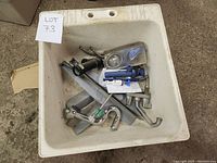 Photo showing off-white square laundry tub with various plumbing fixtures inside.