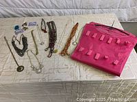 Jewelry storage organizer, assorted necklaces, and hair accessories laid out on a bed.