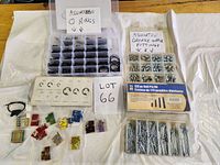 Photo showing assorted O-rings in a compartment box, assorted grease nipple fittings in another compartment box, various blade fuses of different colors and sizes, and a large set of roll pins, all laid out on a white cloth.