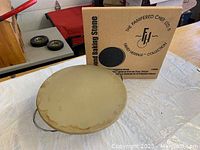 Photo of Pampered Chef pizza stone on metal stand with box in background