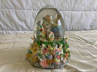 Front view of the spring musical globe showing the glass dome with bunny inside and colorful bunny figurines on the base.