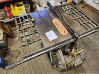 Top view of the metal 10-inch table saw surface featuring grid patterned side extensions and central blade opening with motor underneath.