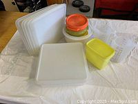 Photo showing all Tupperware containers and lids in the lot including several white square lids, round containers with colorful lids, small yellow container, and two clear measuring cups.
