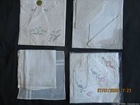 Four groups of folded vintage handkerchiefs showing different embroidery and lace styles on dark background