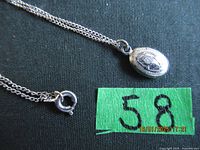 Photo showing full chain with pendant and clasp on black fabric background.