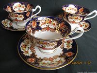 Three Royal Albert Derby pattern tea cups with matching saucers displayed on a black background, showing design and condition.