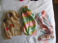 Three vintage silk scarves laid flat on a white patterned surface, showing colors and signatures