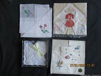 Top view of four folded embroidered handkerchiefs laid flat on black surface, showing floral patterns and lace edges.