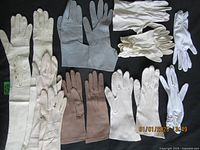 Nine pairs of women's vintage gloves in various colors and styles laid flat on a black surface, showing overall lot contents with close detail on buttons and stitching visible.