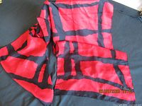 Photo showing large red and black patterned silk scarf fabric, highlighting the color and design.
