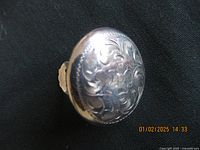 Front view of large round dome sterling silver earring with floral and scroll engraved design.