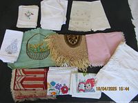 Overview of various vintage and antique linens laid flat. Some linens have embroidery and crochet details.