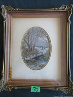 Frontal photo of vintage petitpoint needlework in a decorative carved wooden frame with oval matte and a scenic landscape design.