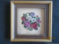 Frontal view of petitpoint needlework floral picture in wooden frame.