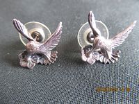 Pair of sterling silver hummingbird earrings on black fabric background, showing front and side angles.