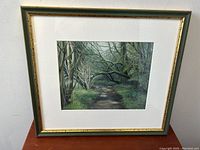 Frontal view of the framed painting showing the wooded path scene.