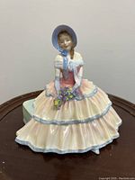 Front angle of the Royal Doulton Day Dreams figurine showing pastel dress and bonnet hat.