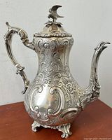 Front and side view showing detailed engravings, serpent spout and ornate handle on silverplated teapot.