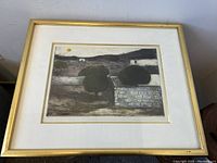 Overall view of the framed artwork showing landscape etching inside gold frame.