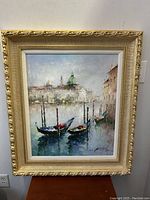 Front view of the gilt framed oil painting depicting Venetian boats and cityscape.