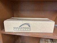 Cardboard shipping box with Smartech Products logo on the side, contains items.