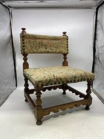 Side angle view of the antique child's chair showing wood frame and upholstery with rabbit design.