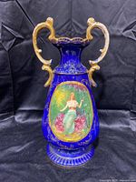 Tall cobalt blue vase with dual gold handles and a central oval painting of a woman.