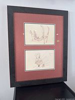 Full view of framed double animation sketches of Goofy and Mickey Mouse in black wooden frame with red mat