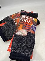 Four pairs of black and grey heated socks with packaging showing 'Heated Sox' and thermal features