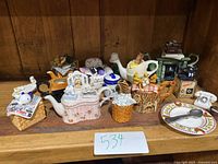 Front overall view of the ceramic miniature tea kettle grouping showcasing various whimsical designs and figurines.