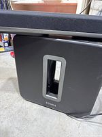 Front view of black Sonos subwoofer on concrete floor
